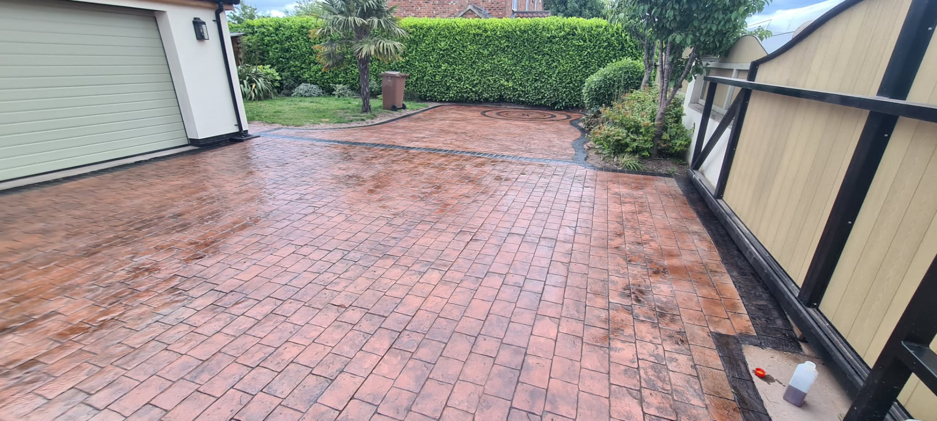 Red brick pattern imprinted concrete driveway beside a garage