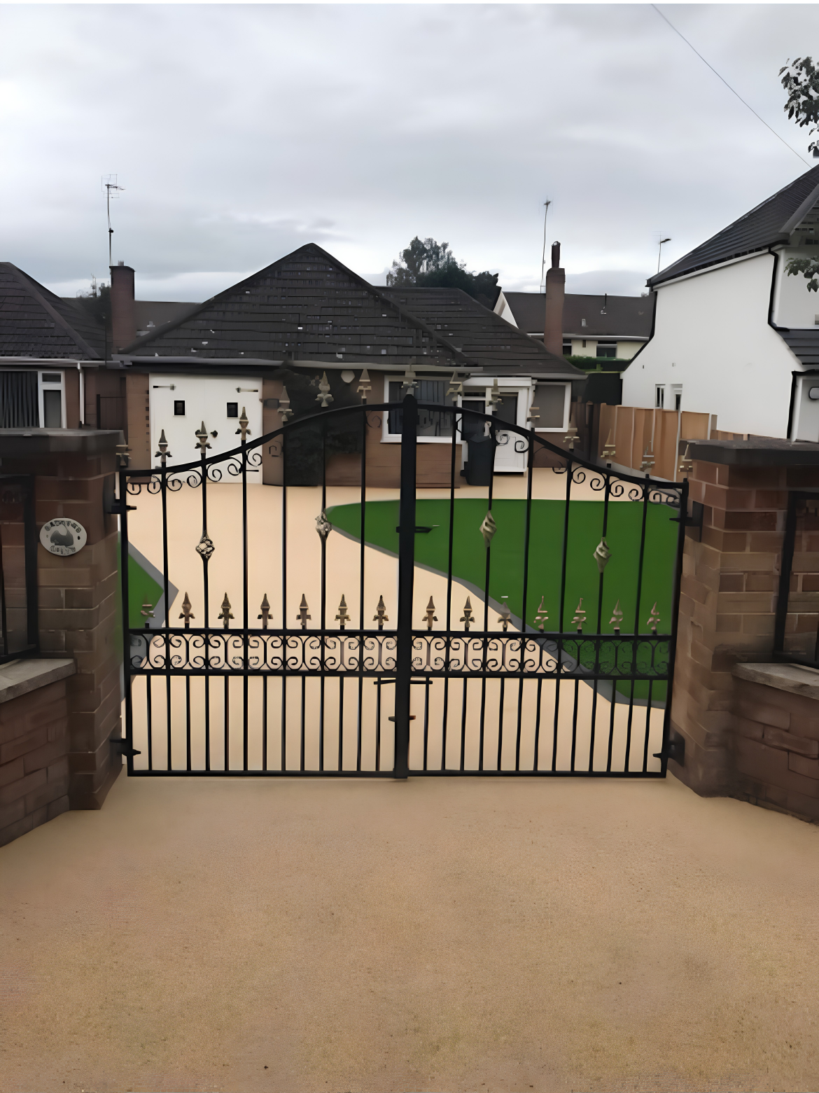 Cream resin bound driveway behind wrought iron gates